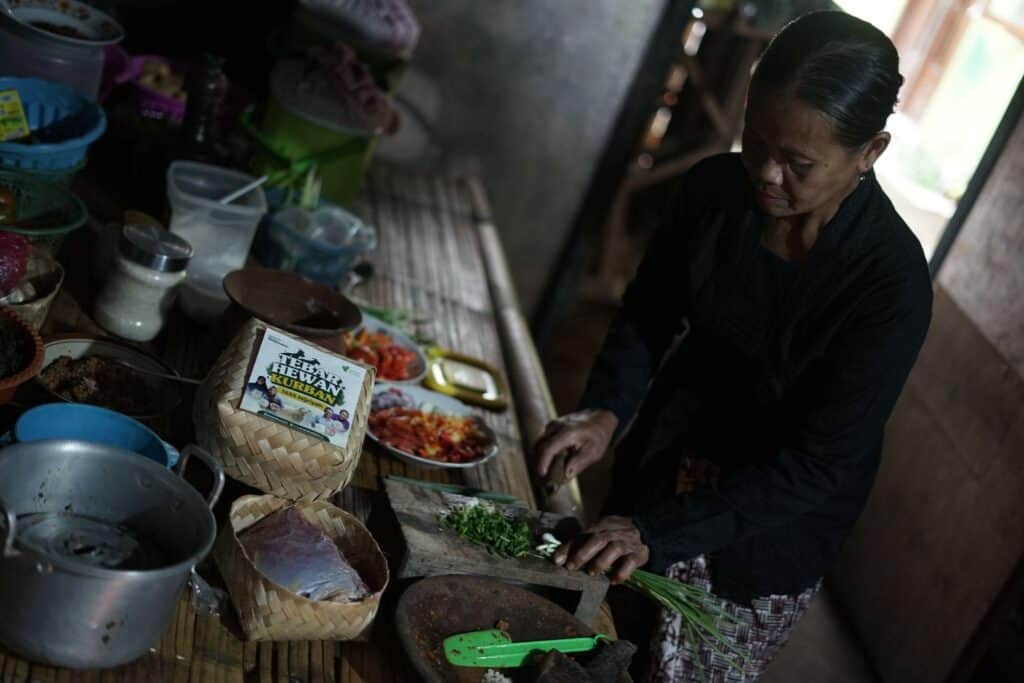 Andiyah (50) dengan menggunakan baju adat Gedegan sedang mengolah daging kurban menjadi masakan khas Osing yaitu Kalak. 