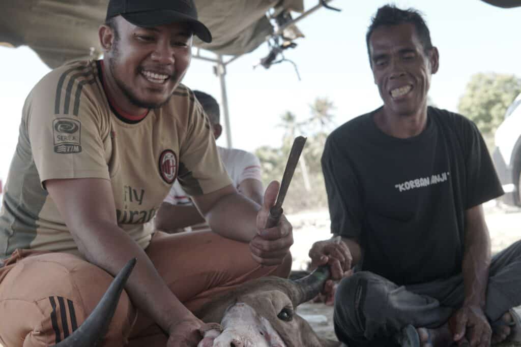 Warga Desa Papela bergotong royong memotong daging-daging kurban untuk dibagikan kepada sesama warga.