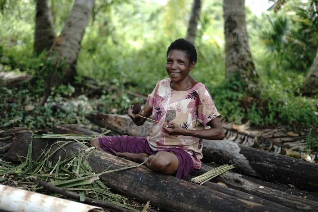 Salah satu warga Papua tengah membuat tusuk sate berasal dari kerangka daun kelapa.