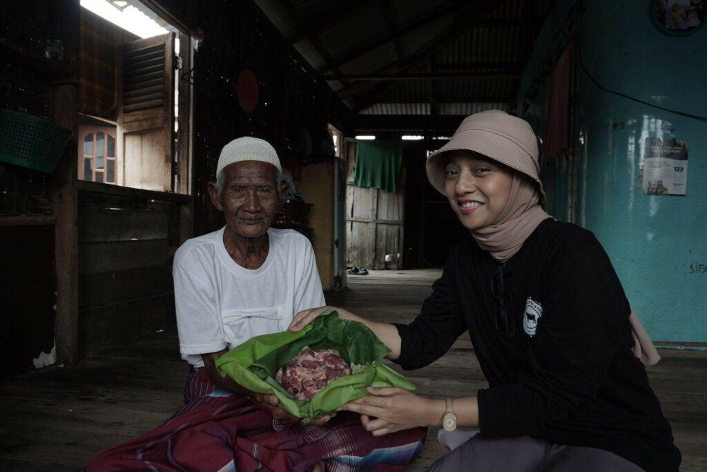 Chiki Fawzi memberikan daging kurban kepada Ahmad (98), warga dusun 2 Desa Jaring Halus.