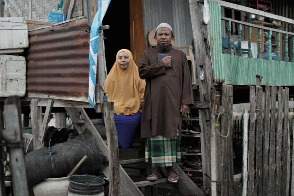 Busron Daeng Kawang (kanan) bersama istri, Santi (kiri), di halaman rumah panggungnya.