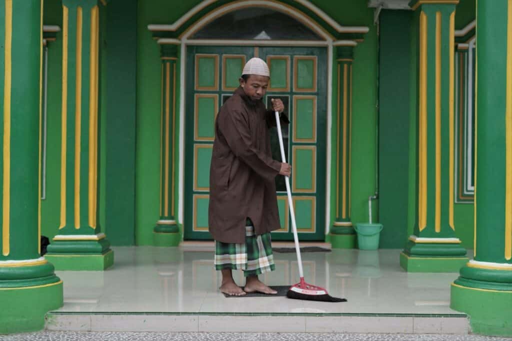 Busron Daeng Kawang membersihkan Masjid Al Muhajirin Manyumbeng (masjid sekitar dekat tempat tinggalnya sekarang di wilayah Kelurahan Biringkassi, Kecamatan Binamu, Jeneponto) guna persiapan solat dzuhur selepas berjualan ikan.