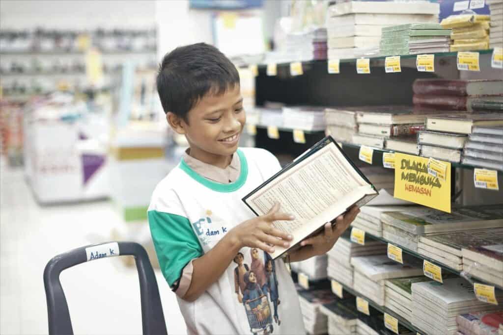 Adam tengah memeriksa tiap halaman dari Al-Quran yang akan dibelinya. 