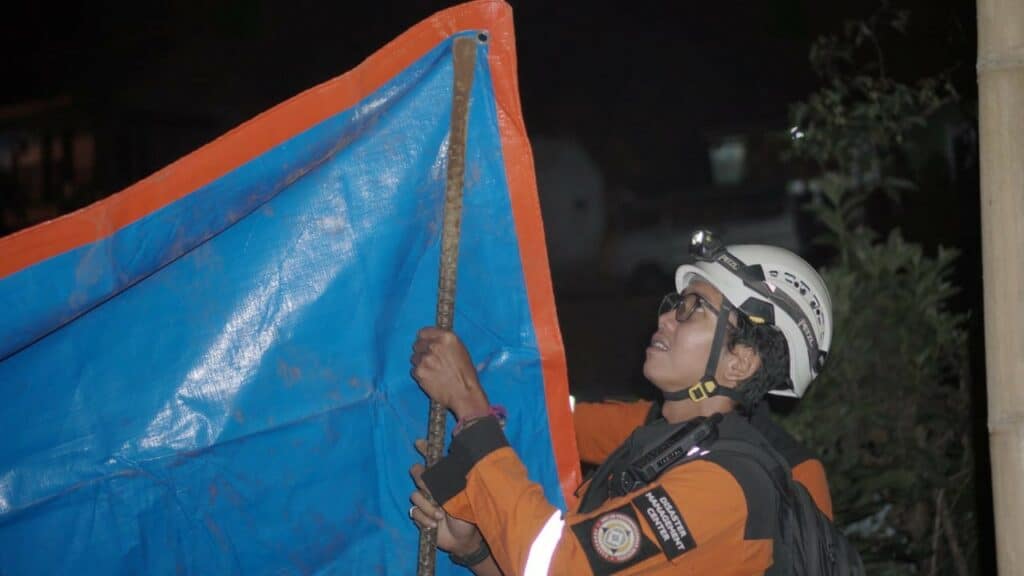 Taqi membantu para pengungsi mendirikan tenda darurat dari terpal sebagai tempat tidur sementara.