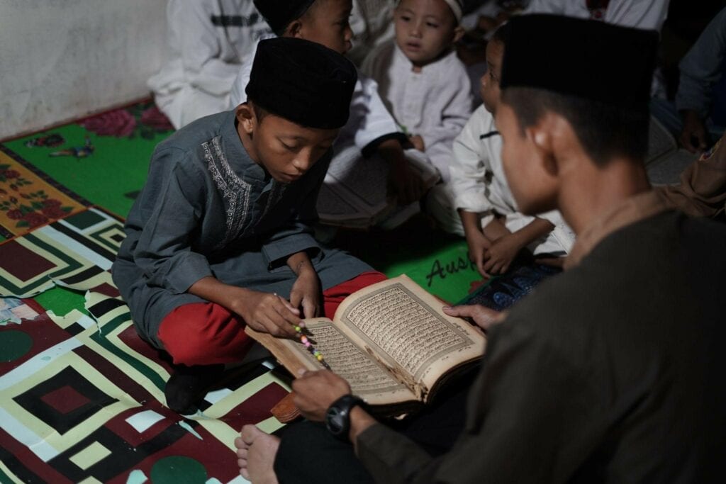 Seorang santri santri TPA Nurus Salam membaca mushaf Al-Qur'an lama miliknya.