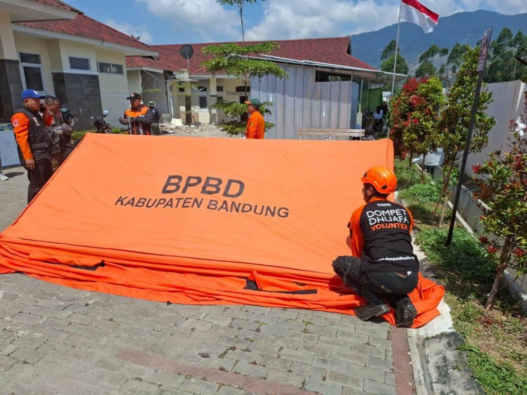 Tim Dompet Dhuafa Jawa Barat bersama BPBD Kabupaten Bandung sedang mendirikan tenda darurat.