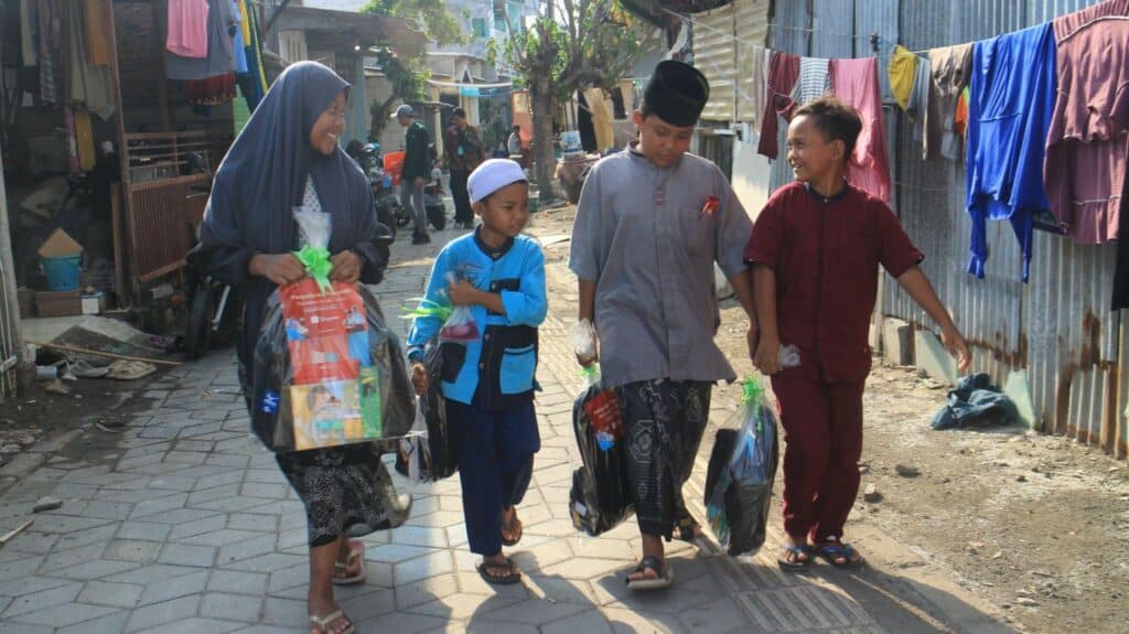 Anak-anak penuh semangat setelah menerima paket school kit pada program Santunan Anak Yatim di Kampung Nelayan, Kawasan Mangrove, Kec. Gunung Anyar, Surabaya pada Kamis (21/11/2024).