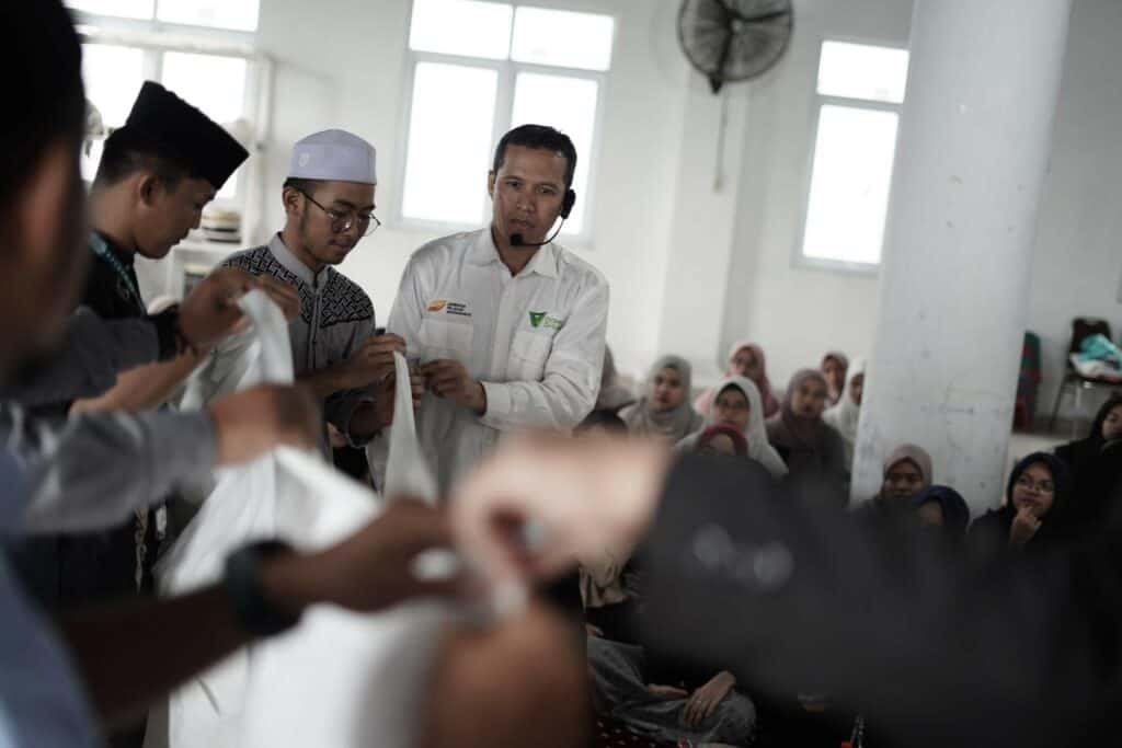 Ust. Madroi dan para peserta mempraktekkan bagaimana cara memotong kain kafan untuk jenazah bagi calon relawan kampus Unida.